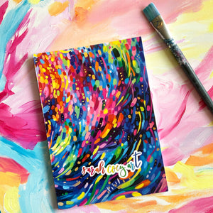Sarah Coey colourful artwork on a sketchbook with a paintbrush beside it resting on a painted background